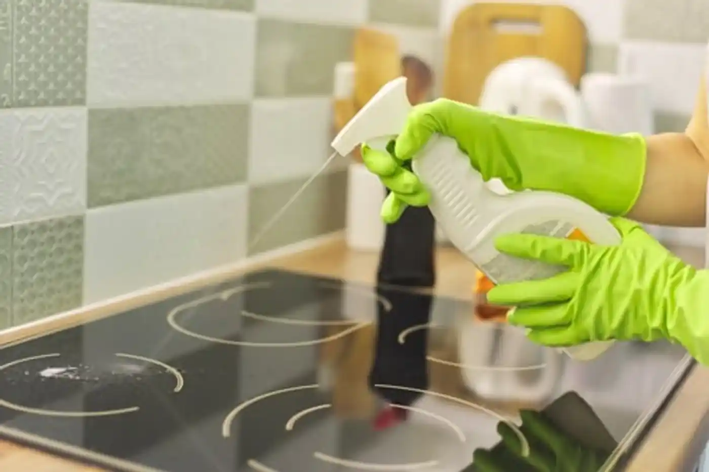 Wiping a glass cooktop clean with a microfibre cloth and spray