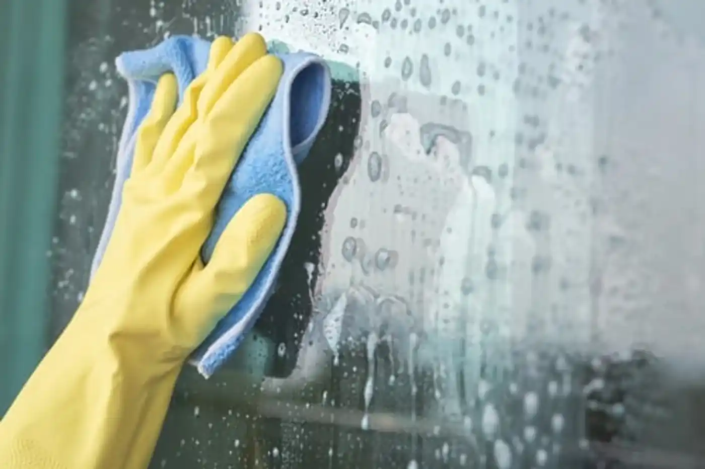 Squeegeeing a glass shower screen clear during a scheduled cleaning visit